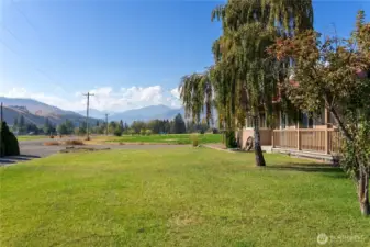 Well-kept front yard with open lawn space, covered porch entry, and panoramic hillside views.