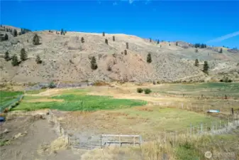 Fenced pasture with open fields, irrigation, ideal for livestock or agricultural use, surrounded by panoramic mountain views.