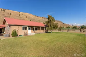 Charming front elevation with metal roof, covered porch, and welcoming landscaping — framed by mountain scenery.