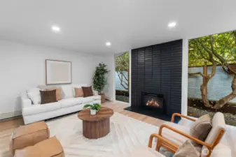LIVING ROOM | This living room at the front of the home features a gorgeous fireplace flanked by stunning floor-to-ceiling windows that are so clear you might feel like you can walk right through. All new lighting has been installed to make this a bright, modern space to chill.