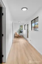 THE WEST WING | Through the drop zone you enter the hallway that leads to the laundry room on the left and the 2nd primary bedroom at the end. A graceful sitting area could also be the perfect nook for a desk.