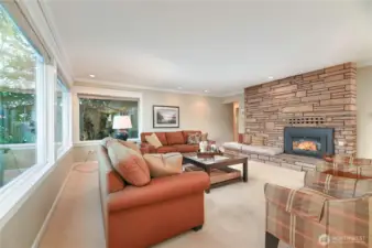 A true Mid-Century living room with a spacious gathering area, dramatic corner wrap windows, and a floor-to-ceiling fireplace that anchors an expansive, conversation-ready seating space.