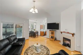 Warm and inviting family room with gas fireplace, hardwood flooring, and sliding glass door leading to the covered outdoor space.
