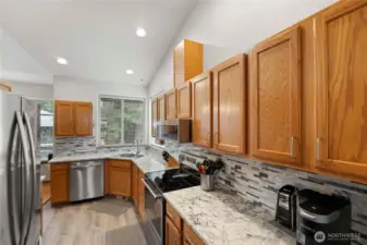 Bright kitchen with Quartz countertops, tile backsplash, stainless steel appliances, and generous cabinet space.