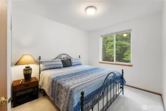 Comfortable bedroom with soft natural light and peaceful views of the surrounding trees.