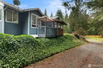 Side view of the home with deck and gazebo overlooking the peaceful, tree-lined property.