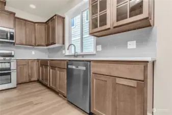 A set of glass panel cabinets and full tile backsplash are charming accents to the Shaker style cabinetry.Photo from same plan on different lot, finishes and features will vary.