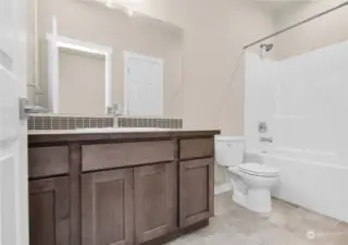 Full guest bath featuring Shaker style cabinetry and contemporary fixtures. Photo from same plan on different lot, finishes and features will vary.