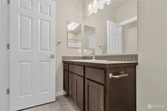 The hall bathroom offers lovely design details including accent tile backsplash and sconce lighting fixtures. Photo from same plan on different lot, finishes and features will vary.