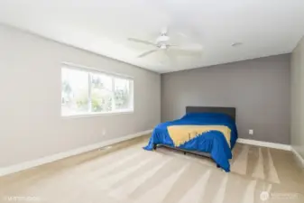 "Spacious primary suite with ceiling fan and large windows for natural light."