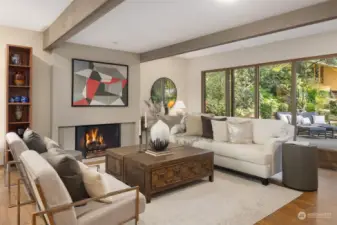 Custom fireplace, wood beams, french doors, and a wall of windows in this living room looking out on the gardens.
