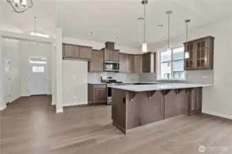 Kitchen features Sable-stained Maple Shaker-style cabinets with quartz countertops and full tile backsplash and extended eating bar.
