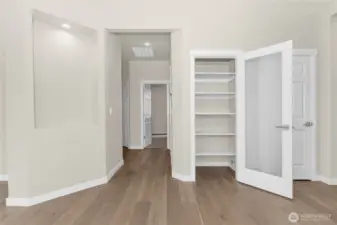 Decorative wall niche and pantry closet with solid shelving and frosted glass door for easy access from kitchen.