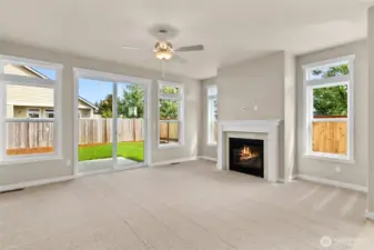 Living room with plenty of natural light featuring cozy gas fireplace with tile surround and ceiling fan.