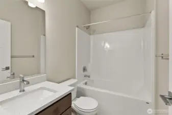 Full bathroom with undermount sink in Shadow-stained Maple cabinetry, quartz countertop with backsplash and tub/shower.