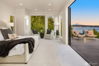 Upper-level primary suite with operable window walls opening to a private deck, blending indoor comfort with panoramic views of Lake Washington and Mount Rainier