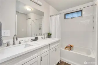 Main floor bathroom offers a soaking tub/shower w/ tiled walls and double sink vanity.