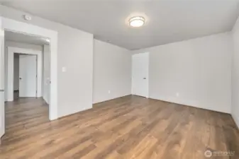 Showing the door to the walk-in-closet in the Primary Suite and into the hall toward the 2nd bedroom upstairs and office space on the landing.