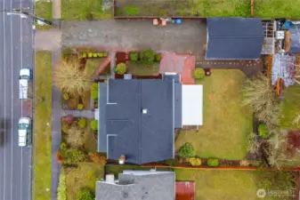 Aerial view of the lot- showing the partially fenced backyard, fruit trees, and detached 1-car garage.