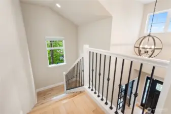 A light-filled staircase highlights the striking light fixture and impressive two-story entryway.