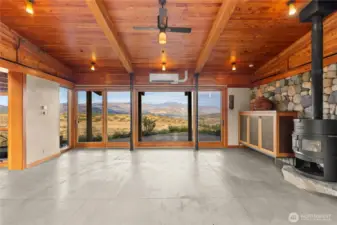 Enter directly into the main living area with a wall of windows opposite showcasing dramatic valley and mountain views. A Danish brand wood stove (Rais) keeps off the winter chill while two large glass sliding doors opposite offer access to the cement patio beyond and allow cooling breezes in. Custom metal see-through screens slide across the west-facing wall of windows for interior shade while maintaining the view on hot summer afternoons.