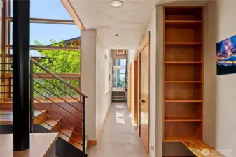 Looking back down light-filled the hallway toward the screened porch. Stairs down to the three car garage are just to the left, with a convenient bench and built in shelves to catch you and your things when you arrive home. Up the stairs to the left is a flexible-space studio or 1 bedroom apartment.