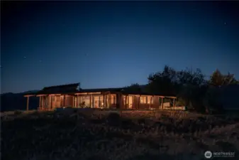 Nestled into the landscape beneath a big dark sky, soft light and lots of wood create a feeling of retreat.