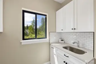 This laundry room makes doing laundry a pleasure.  Wonderful window to allow in the fresh air and the light. Sink in the laundry room, A MUST. Lots of cabinetry is a plus