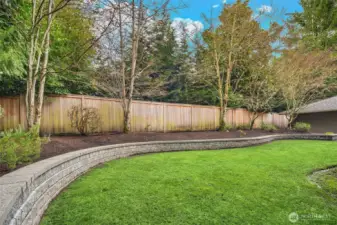 Level, grassy play lawn surrounded by a terraced planting bed.