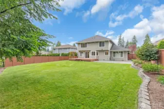 A spacious Trex deck and patio, surrounded by lush greenery on a green belt, provides privacy for relaxation and entertaining.