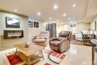 A large, flexible space staged for both living and sleeping, complete with a newer wall-mounted fireplace—ideal for a studio-style setup or comfortable guest quarters. A large wall-mounted TV is also included (not pictured).