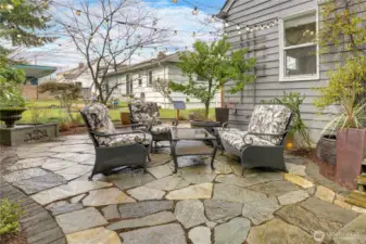 This flagstone patio offers a tucked-away outdoor retreat, complete with a water fountain that adds a soothing, relaxing ambiance. Photo was taken prior to installation of the new fence, which has since been completed to provide enhanced privacy from the neighboring yard.