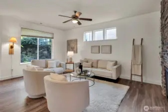 A light and bright family room has a large picture window accentuating the outdoor landscape.