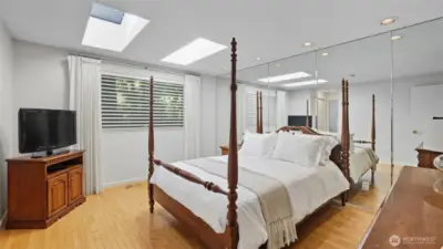 Spacious primary suite filled with natural light from skylights and large windows.
