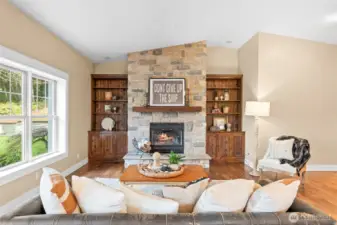 The hub of this home is the large living room off the kitchen featuring a stone fireplace, wood floors, solid wood built-ins, and vaulted ceilings.