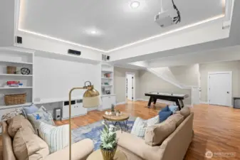 Basement living room with built-in projector and integrated screen is the perfect spot to watch the game with friends or take in a movie night.