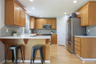 Updated kitchen combines warm cabinets, bright quartz counters, and stainless steel appliances for a modern and inviting space.