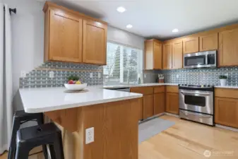 Eat-in bar counter provides wonderful connection to main living space, and easy conversation spot. Tile backsplash ties in the subtle colors and adds a stylish element.