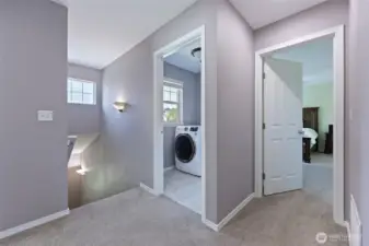 Roomy landing at the top of the stairs leads to beds/bath, laundry, and primary bedroom, seen here.