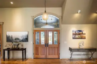 Impressive foyer with soaring ceilings, rich hardwood floors, and beautiful double entry doors topped with a decorative transom window.
