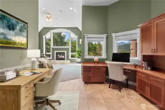 Thoughtfully designed entry to the primary suite featuring a built-in workspace and custom cabinetry, leading into the expansive bedroom with fireplace and dramatic arched windows capturing scenic views.