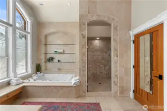 Elegant spa-style primary bath highlighted by a jetted soaking tub, stunning tiled walk-in shower, and custom architectural tilework with built-in niches.