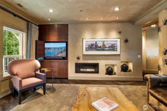 A sleek linear gas fireplace is framed by custom Bubinga wood cabinetry with a tri-fold media cabinet, blending warmth, function, and modern design.