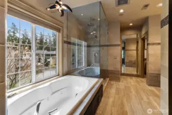 An oversized glass walk-in shower and jetted soaking tub sit alongside a large window with Hunter Douglas remote-controlled blinds, creating a space designed for effortless relaxation.