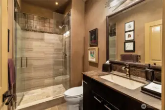 The guest bathroom features a marble-topped vanity and a glass walk-in shower, offering a clean and comfortable space for everyday use.