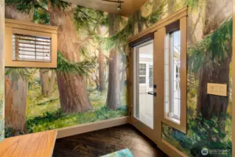 The entry marks the beginning of an 80-foot custom mural by local artist Jennifer Bowman, with direct access to the front deck extending the experience outdoors.