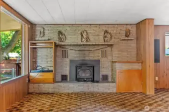 Petrified wood features in brick fireplace. Living room is carpeted.