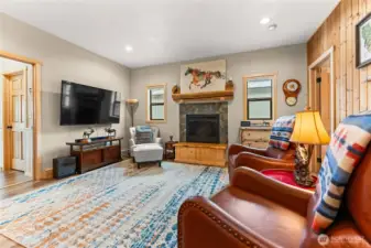 A welcoming living room with rustic accents, a cozy fireplace, and ample seating — ideal for relaxing or entertaining. Stylish décor and warm tones enhance the inviting ambiance.
