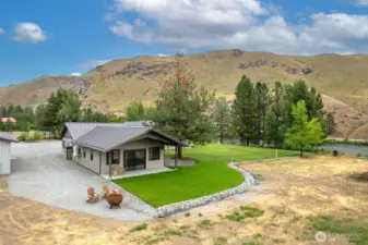 Enjoy serene outdoor living with a lush green lawn, cozy fire pit seating, and stunning mountain views. The covered patio provides the perfect spot to relax or entertain while overlooking the surrounding natural beauty.