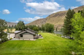 This stunning aerial view showcases the home’s unmatched setting, where lush green lawns stretch to meet the scenic river. With dramatic hillsides as a backdrop, this property offers both wide-open space and incredible privacy.